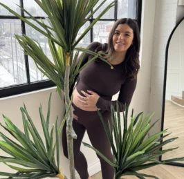 Laura Holland, pelvic physio, standing behind a plant